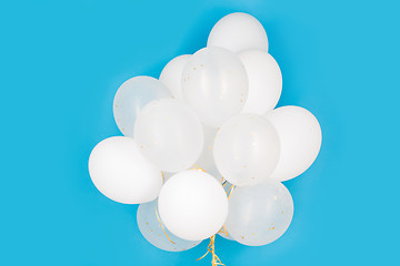 Image showing close up of white helium balloons over blue