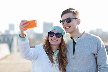 Image showing smiling couple with smartphone taking selfie