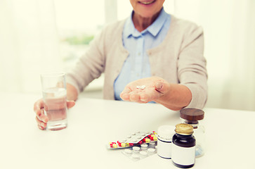 Image showing happy senior woman with water and pills at home