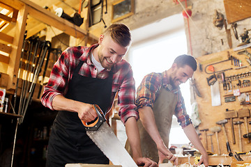 Image showing carpenters working with saw and wood at workshop