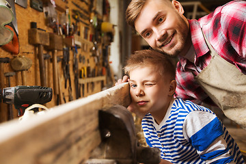 Image showing father and little son with wood plank at workshop