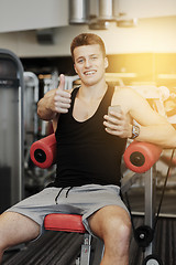 Image showing smiling young man with smartphone in gym