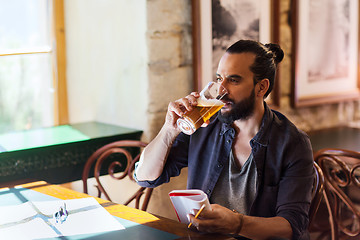Image showing man with notebook drinking beer at bar or pub