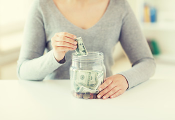 Image showing close up of woman hands and dollar money in jar