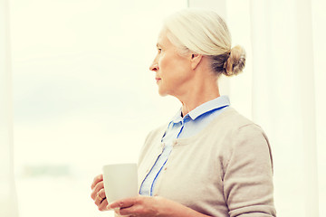 Image showing lonely senior woman with cup of tea or coffee