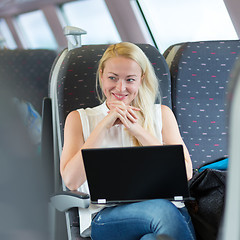 Image showing Woman smiling while travelling by train.