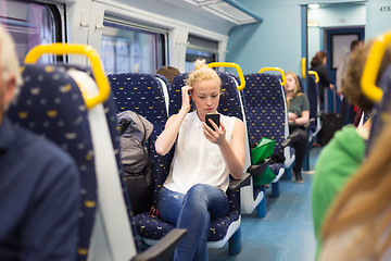 Image showing Woman using mobile phone while travelling by train.