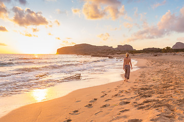 Image showing Woman walking on sand beach at golden hour