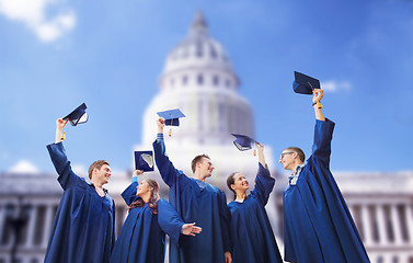 Image showing group of happy students waving mortarboards