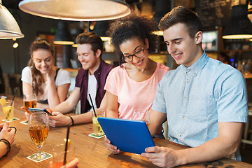 Image showing happy friends with tablet pc and drinks at bar