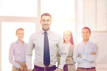 Image showing smiling businessman in office with team on back