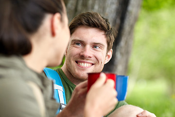 Image showing happy couple with cups drinking tea in nature