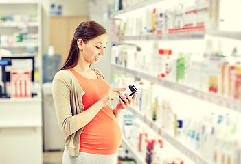 Image showing happy pregnant woman with medication at pharmacy