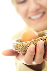 Image showing Mature woman holding a nest with an egg