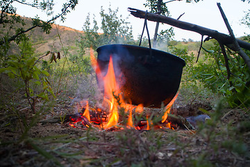 Image showing Camp life. On fire to boil pot of soup for traveler