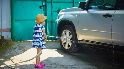 Image showing Little girl helps her parents to wash the car