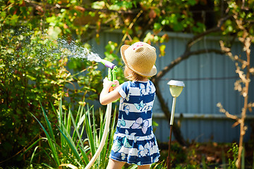 Image showing Little happy girl watering garden