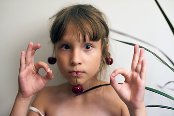 Image showing Little girl with a cherry on her ears