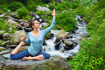 Image showing Sorty fit woman doing yoga asana outdoors at tropical waterfall