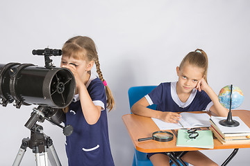 Image showing Girl astronomer looks at the sky through a telescope, the other girl is sitting at the table