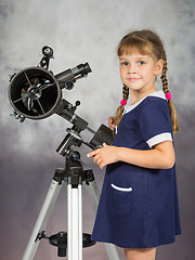 Image showing Girl lover of astronomy stands next to the telescope and looked into the frame