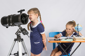 Image showing Girl astronomer looks through the eyepiece of the telescope, and the other girl sitting happily at the table