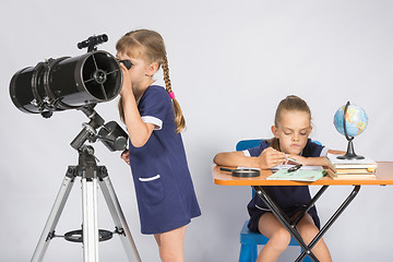 Image showing Girl watching the celestial bodies in the telescope, the other girl is waiting for the results of observations