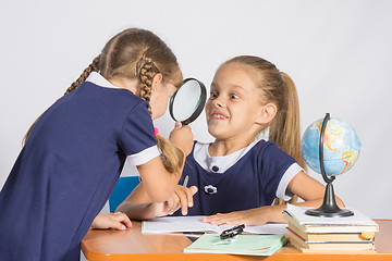 Image showing Girl looking at the other girl with a magnifying glass on a geography lesson