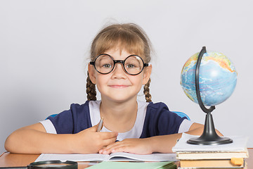 Image showing Happy girl first grader sits at a table