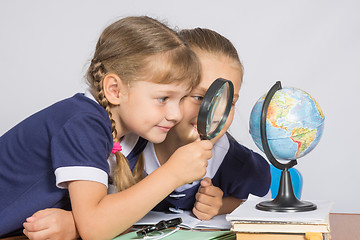 Image showing Two girls girlfriends looking at globe through a magnifying glass