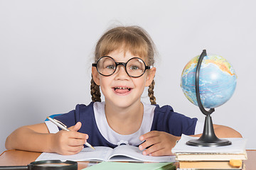 Image showing Happy first grader sits at a table in the classroom, with his mouth open in pleasure