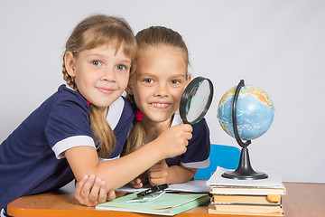 Image showing Two schoolgirls looking at globe through a magnifying glass