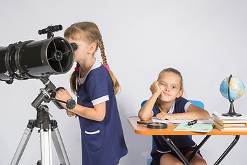 Image showing A girl looks through a telescope, the other girl is waiting sad results