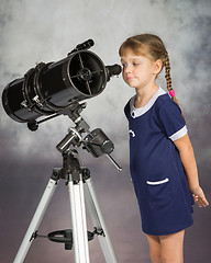 Image showing Girl lover of astronomy with interest looks in the eyepiece of the telescope