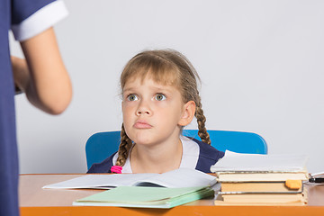 Image showing Schoolgirl sitting at the desk angrily looks at another girl