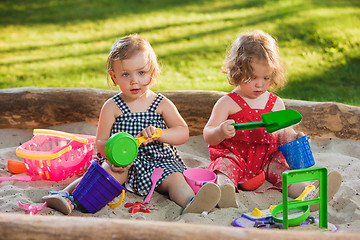 Image showing The two little baby girls playing toys in sand