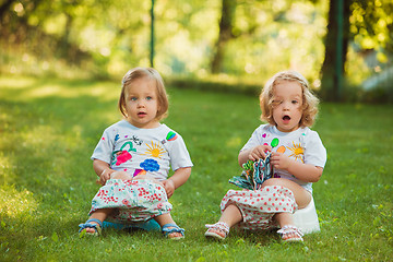 Image showing The two little baby girls sitting on pots