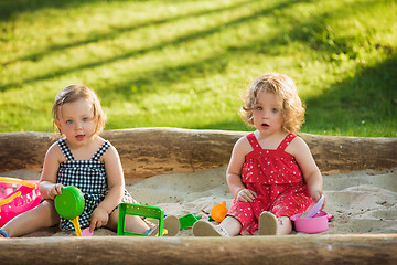 Image showing The two little baby girls playing toys in sand