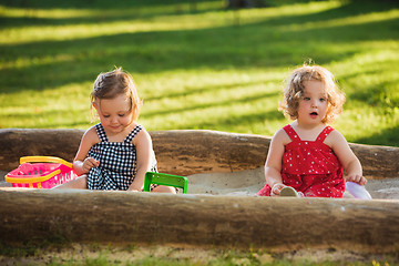 Image showing The two little baby girls playing toys in sand