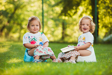 Image showing The two little baby girls sitting on pots