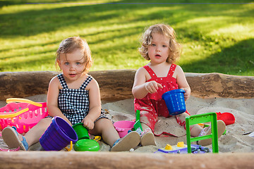 Image showing The two little baby girls playing toys in sand