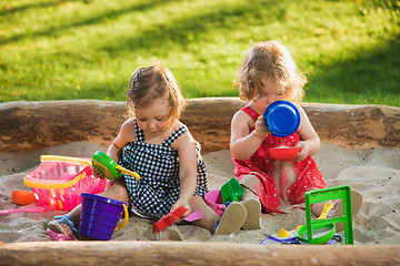 Image showing The two little baby girls playing toys in sand