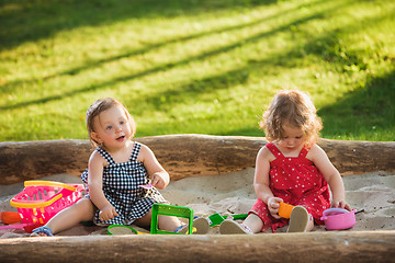 Image showing The two little baby girls playing toys in sand