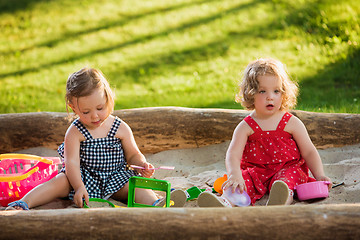 Image showing The two little baby girls playing toys in sand