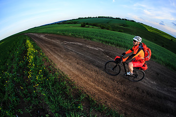 Image showing Mountain bikeer rides on the trail against beautiful sunset