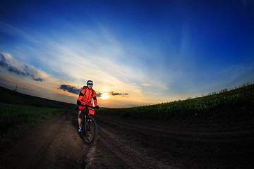 Image showing Mountain bikeer rides on the trail against beautiful sunset