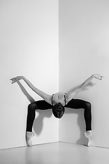 Image showing Ballerina in black outfit posing on pointe shoes, studio background.