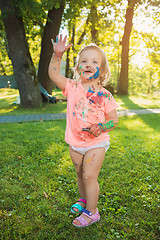 Image showing Two-year old girl stained in colors against green lawn