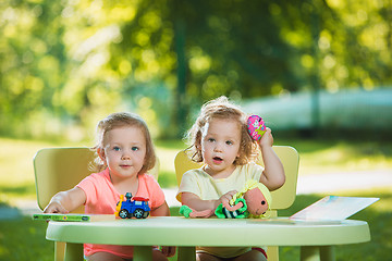 Image showing The two little baby girls playing toys in sand