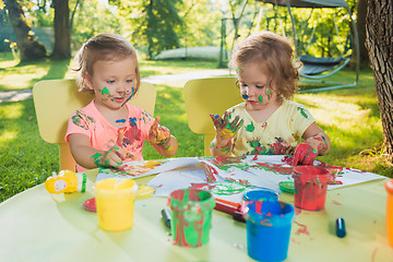 Image showing Two-year old girls painting with poster paintings together against green lawn